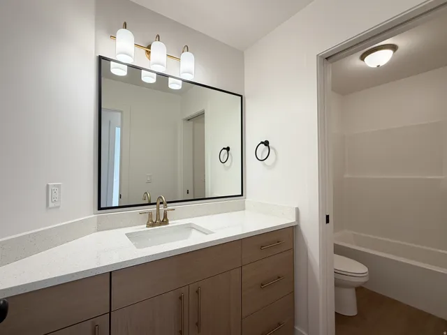 Modern vanity with quartz countertop, undermount sink, and brass-finish faucet