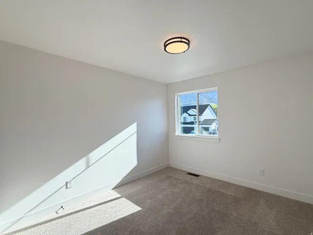Bright upper-level bedroom featuring sloped ceilings with skylights, large window with natural light, neutral wall finishes, and neutral-tone carpeting