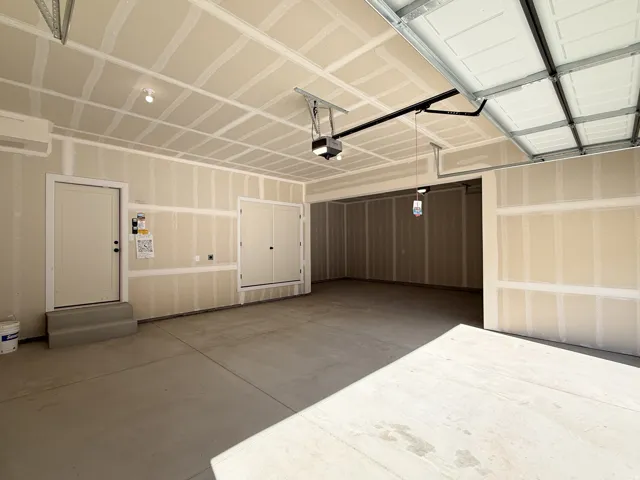 Spacious garage with concrete flooring, automatic garage door opener, and a built-in storage closet