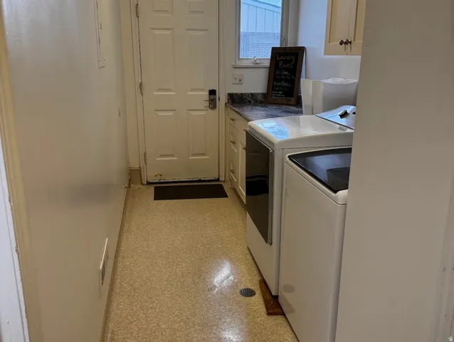 Laundry area featuring light-colored flooring, a solid-panel door, built-in cabinetry, and a window