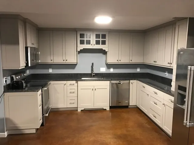 U-shaped kitchen featuring light-toned cabinetry, dark speckled countertops, and stainless steel appliances