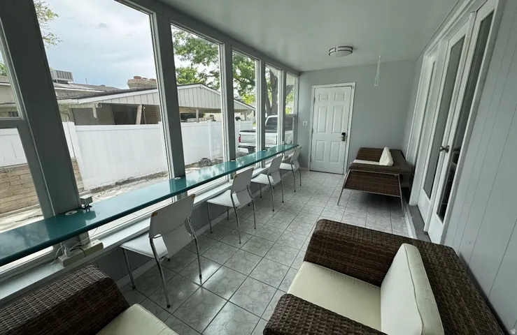 Enclosed sunroom of floor-to-ceiling windows  featuring built-in desk that spans the entire room. The desk features several countertop outlets.