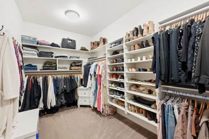 Expansive closet featuring built-in shelving, multiple hanging rods, corner storage, and recessed ceiling lighting