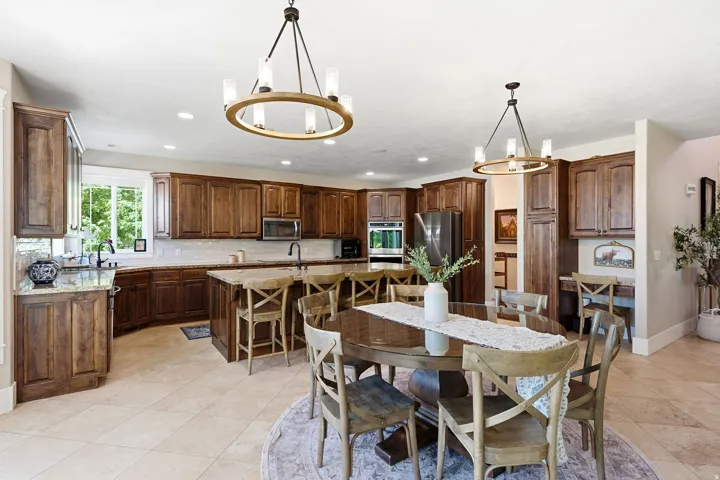 Spacious kitchen featuring extensive wood cabinetry, light-toned stone countertops, and tile flooring