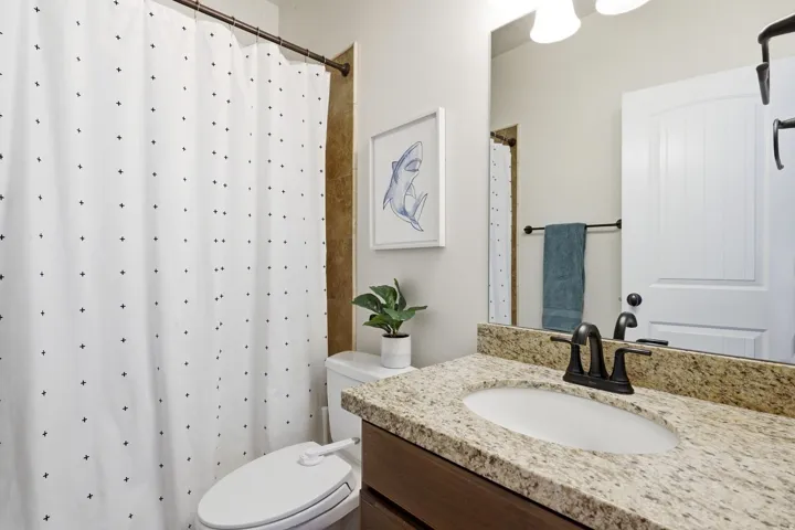 Bathroom vanity with granite countertop, undermount sink, and dark bronze-finish fixtures