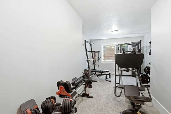 Dedicated exercise space featuring light gray walls, a textured ceiling, a flush-mount ceiling light, and a horizontal window providing natural light