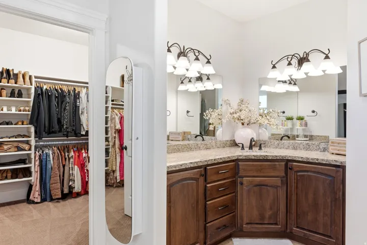 Dual vanity with a corner configuration, granite-finish countertops, and wood-finish cabinetry