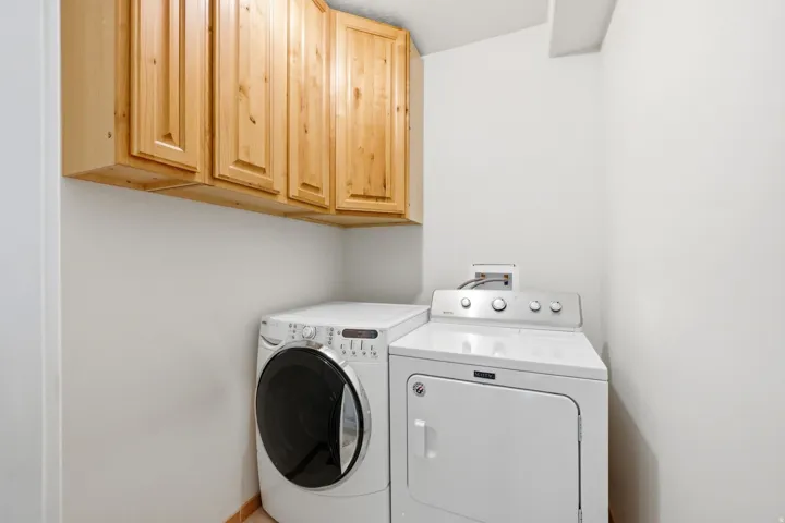 Dedicated laundry area featuring overhead natural wood cabinetry