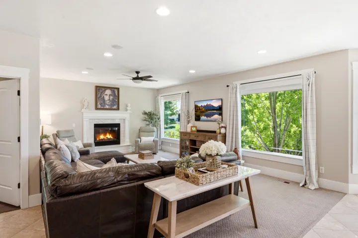 Spacious living area featuring a fireplace with a white mantel, recessed lighting, and a ceiling fan
