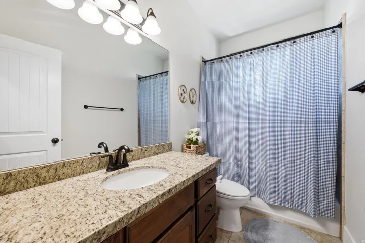 Full vanity featuring a granite countertop with an undermount sink, dark wood cabinetry, and an oil-rubbed bronze faucet