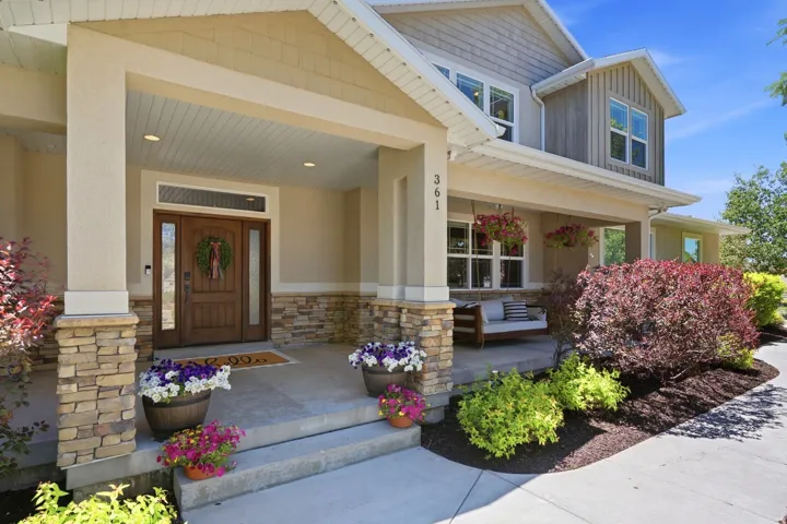 Stone and stucco exterior featuring a covered porch, wood-paneled entry door with sidelights, and recessed lighting