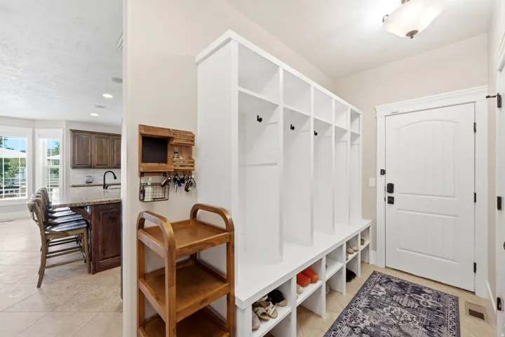 Entryway featuring a built-in white storage system with hooks and integrated shoe cubbies