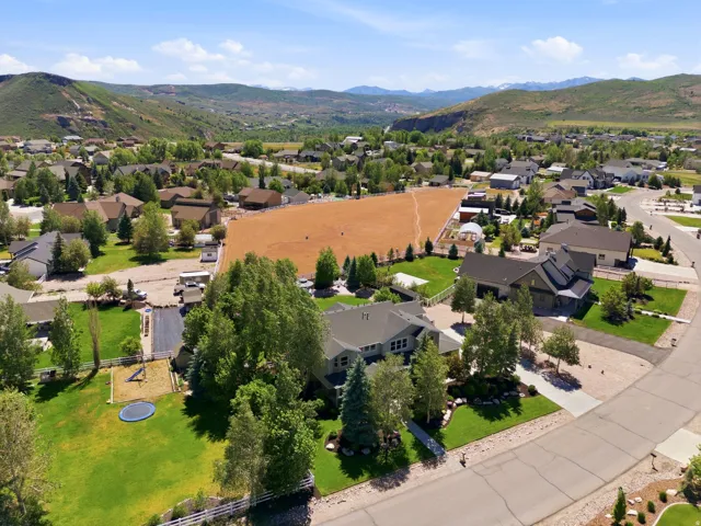 Expansive residential property featuring a large green lawn, mature trees, and a gravel driveway