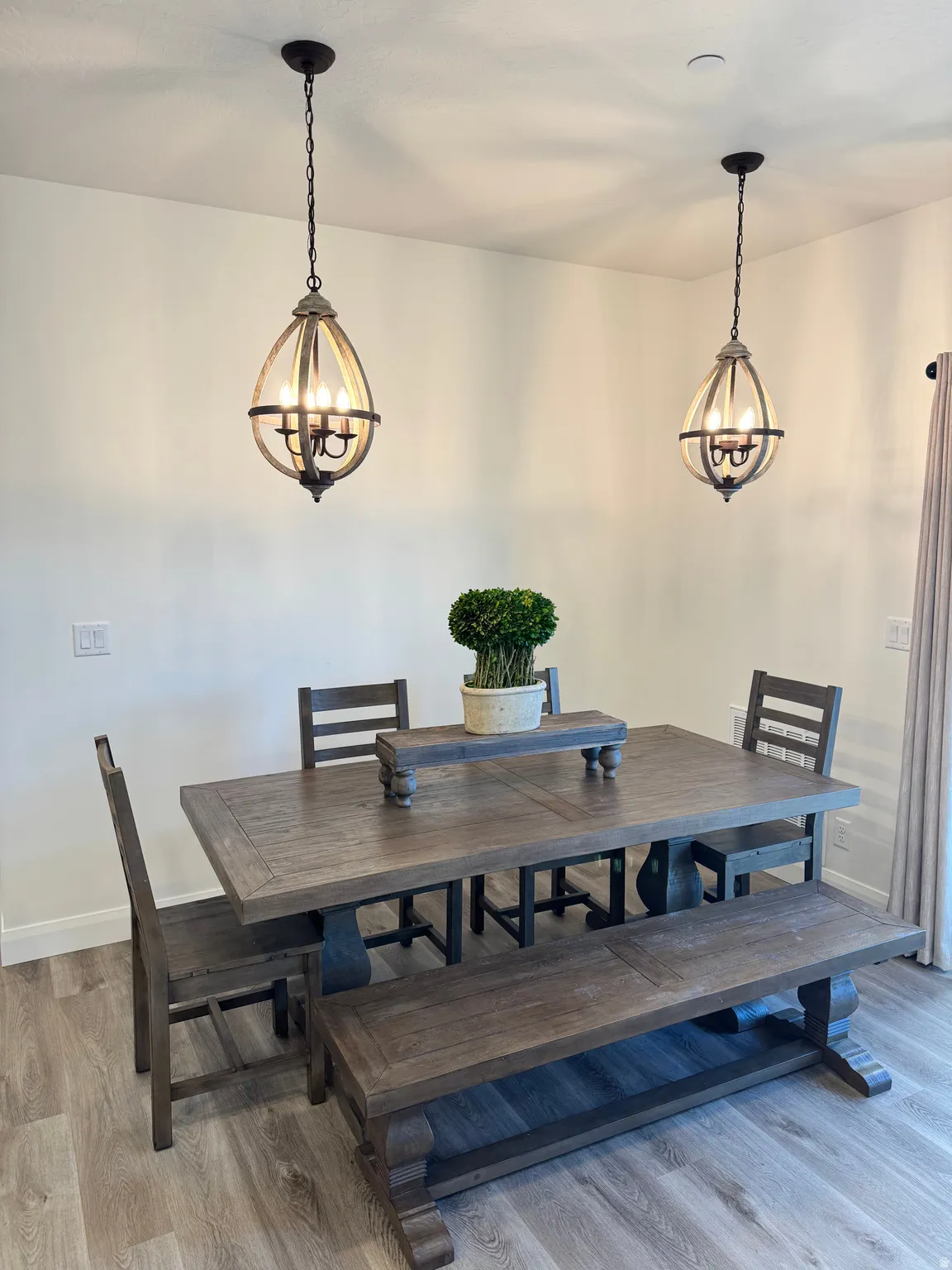 Dining space featuring two pendant light fixtures, light-toned walls, and wood-finish flooring