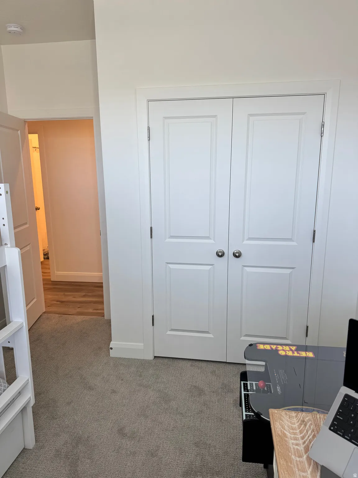 White bi-fold closet doors with polished nickel hardware, light gray carpeting, and white baseboards
