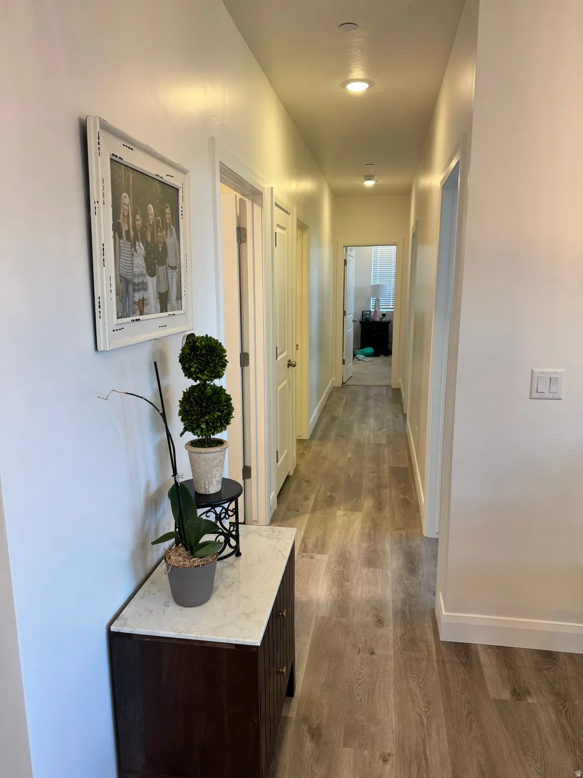Hallway featuring wood-finish flooring, recessed lighting, white walls, and white trim