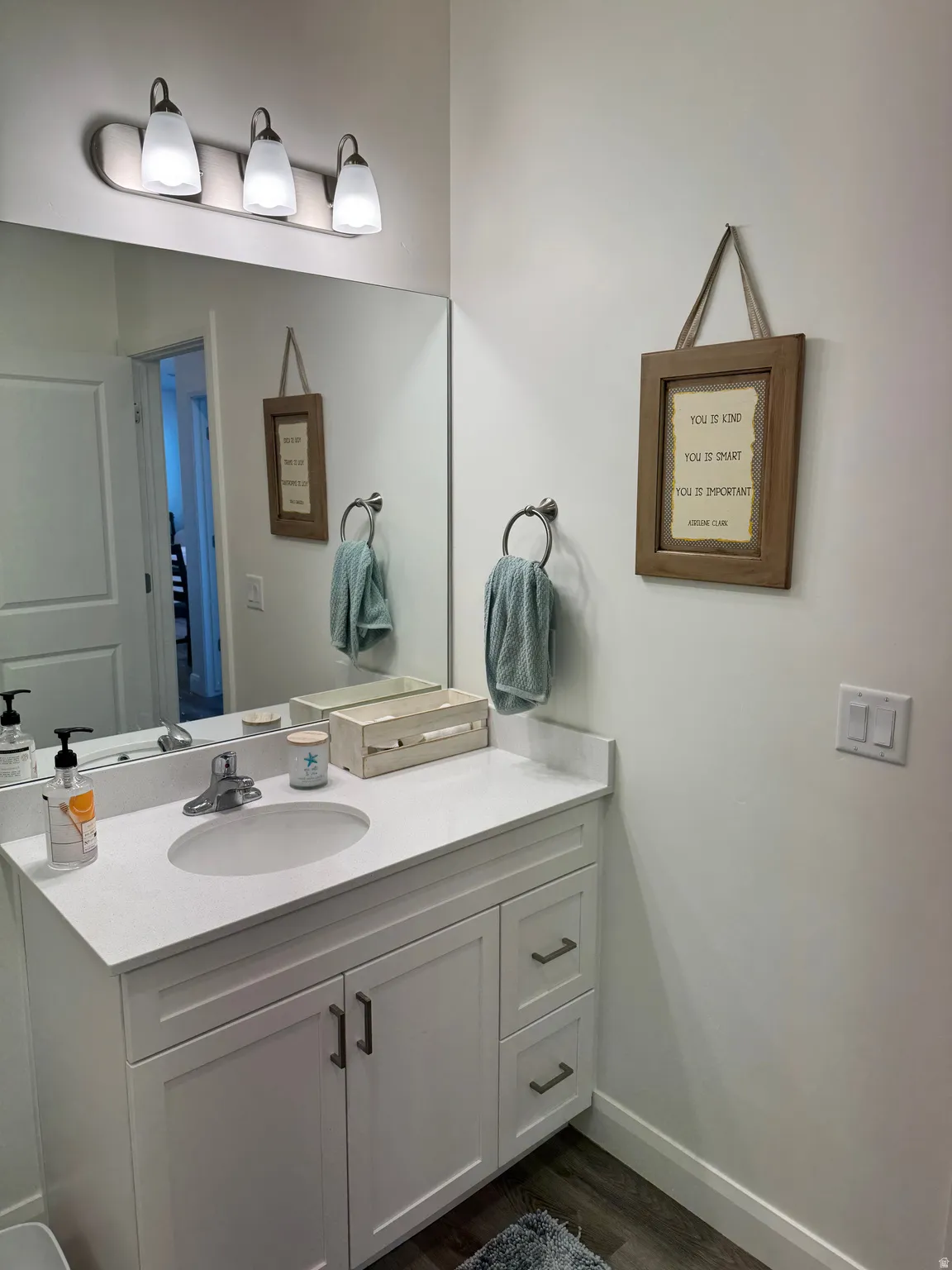 Bathroom vanity featuring a white countertop with an integrated sink, brushed nickel faucet, and white cabinetry with dark hardware