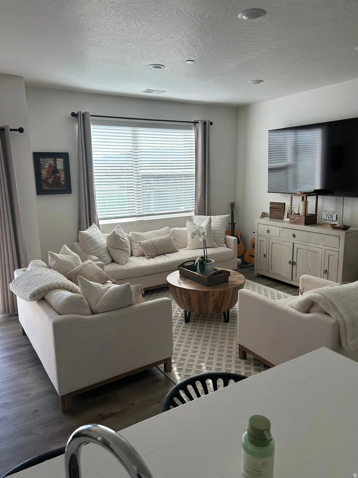 Living area featuring wood-finish flooring, recessed lighting, and a large window with blinds