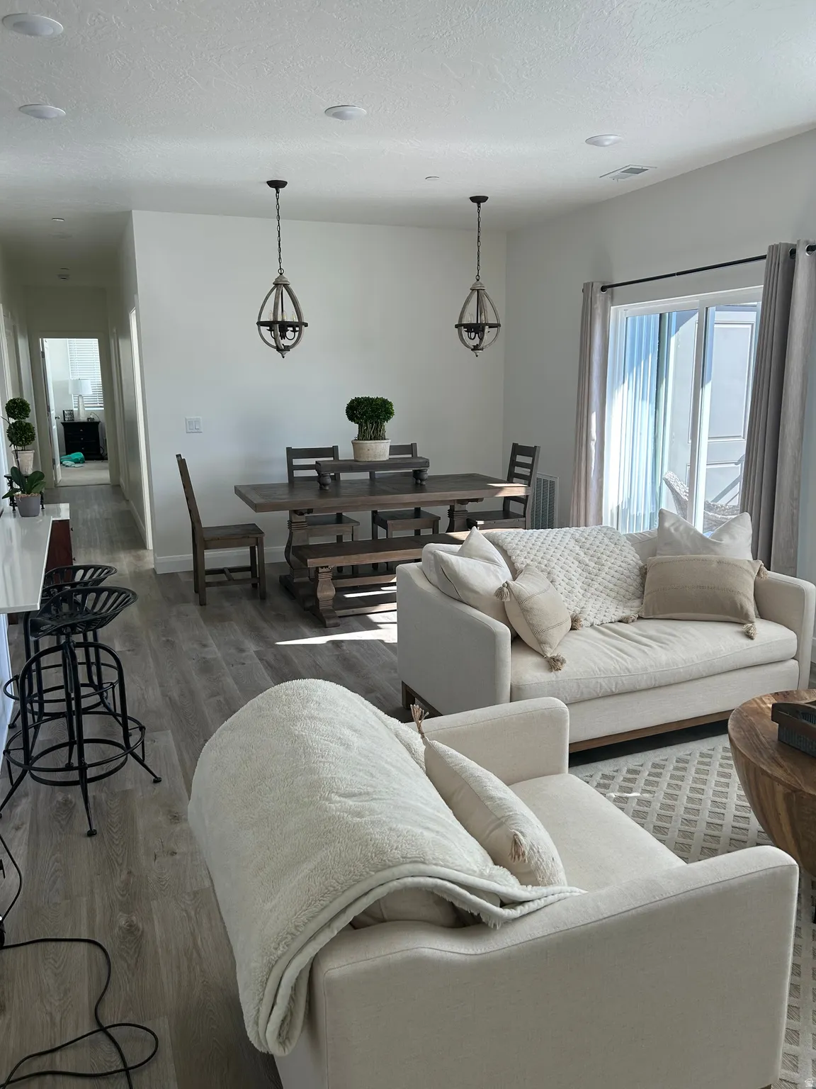 Open-concept living space featuring wood-finish flooring, recessed ceiling lights, and dual decorative pendant fixtures