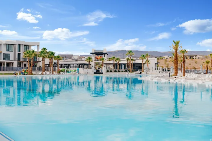 Expansive blue lagoon bordered by modern architecture, palm trees, and a sun shelf with lounge seating