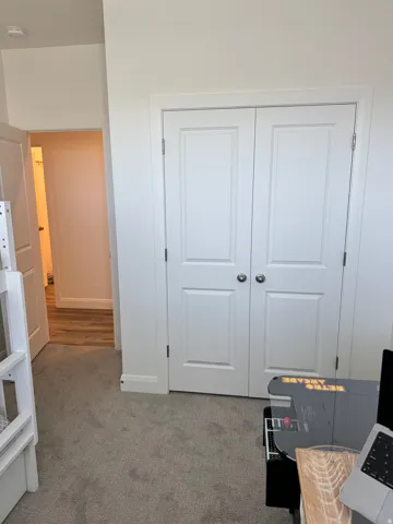 White bi-fold closet doors with polished nickel hardware, light gray carpeting, and white baseboards