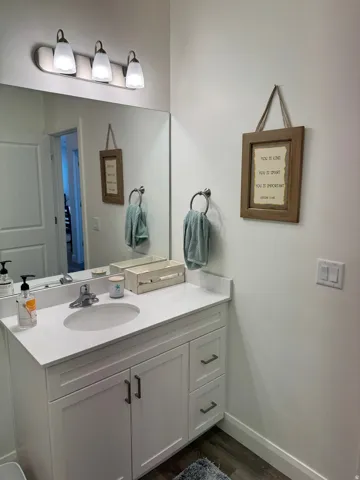 Bathroom vanity featuring a white countertop with an integrated sink, brushed nickel faucet, and white cabinetry with dark hardware