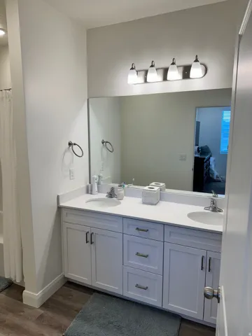 Dual vanity with undermount sinks, white countertop, and light wood-finish flooring