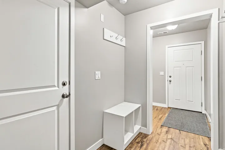Entryway featuring wood-finish flooring, light gray wall paint, and white trim and man door to garage.