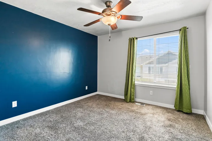 Master bedroom featuring a ceiling fan with light fixture, carpeted flooring, and a large window with blinds