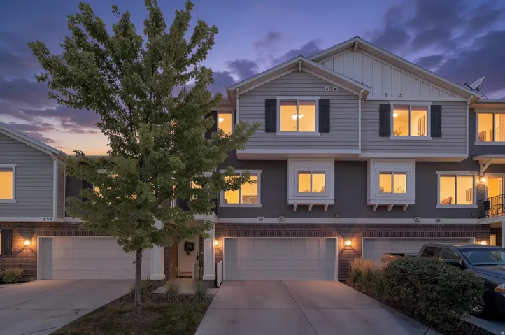 Townhome exterior featuring gray siding, white trim, and a brick foundation