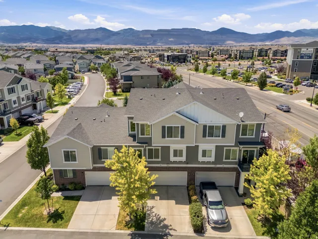 Modern townhome exteriors featuring multi-level construction, attached garages, and mature landscaping