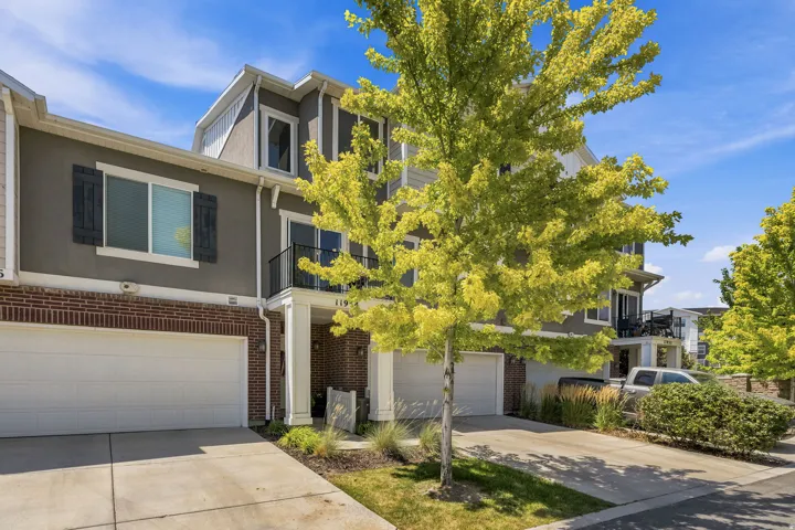 Modern townhome exterior featuring a two-car garage, brick facade, and a second-story balcony