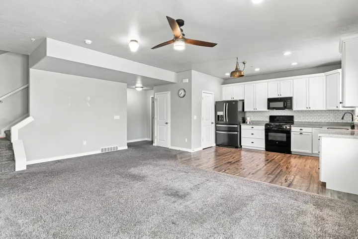 Open-concept living space with gray carpeting and wood-finish flooring
