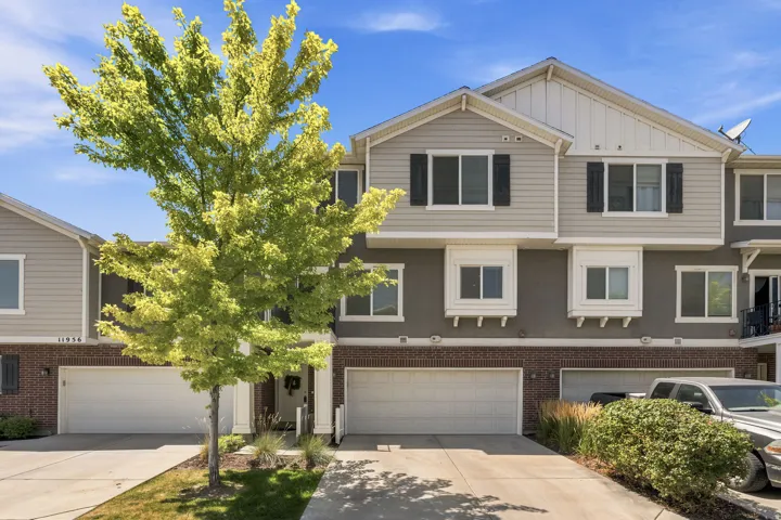 Multi-level townhome featuring a two-car garage, brick facade, and decorative window boxes