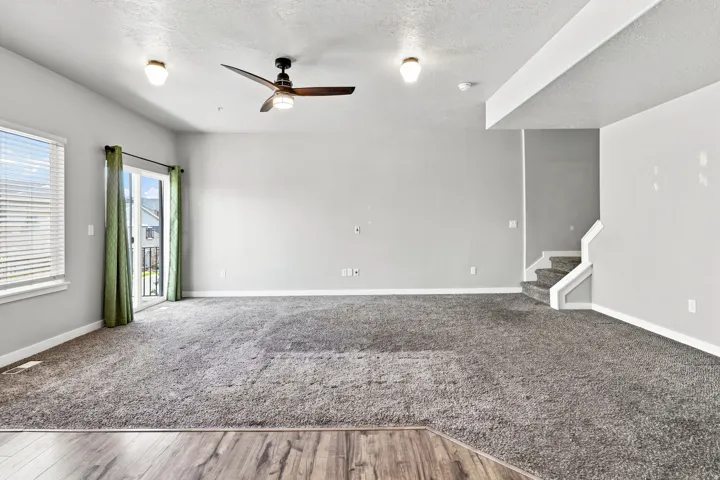 Spacious room featuring gray carpet and a wood-finish flooring transition