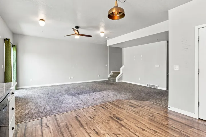 Expansive living area featuring mixed flooring with wood-finish planks and carpet, recessed lighting, and a ceiling fan