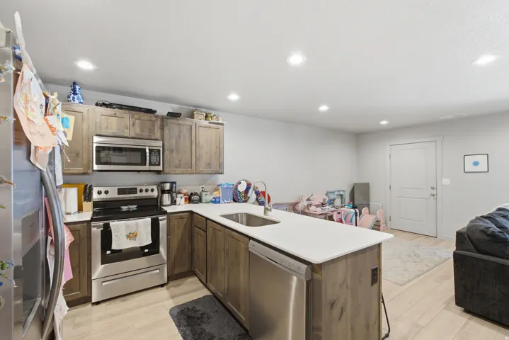 Kitchen featuring stainless steel appliances, wood-finish cabinetry, white countertops, and recessed lighting