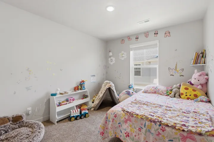 Carpeted room featuring a single window with blinds, a built-in wall shelf, and a ceiling light fixture