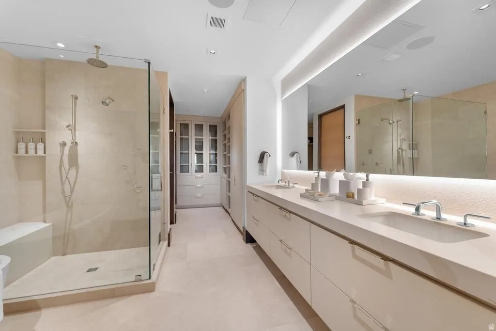 Spacious bathroom featuring a frameless glass shower enclosure with rain shower head and integrated bench