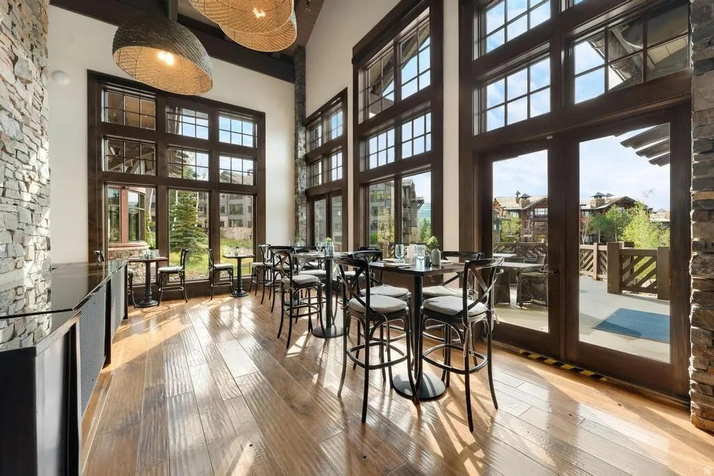 Spacious interior featuring expansive floor-to-ceiling windows with dark wood framing, rich wood-finish flooring, and a stone accent wall