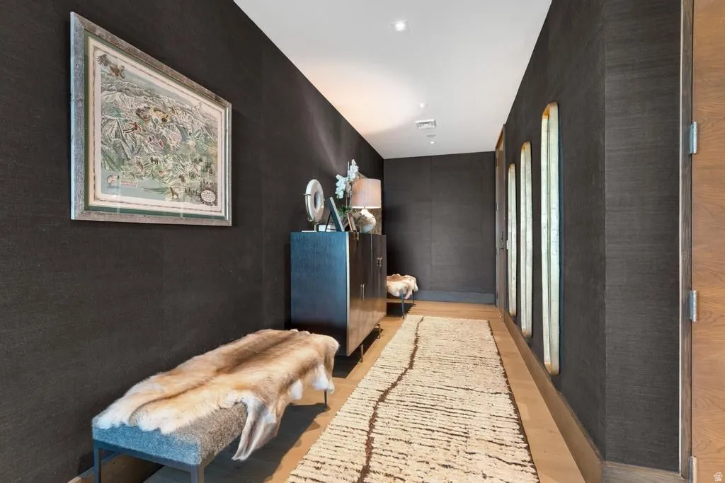 Corridor featuring dark textured wall coverings and wood-finish flooring