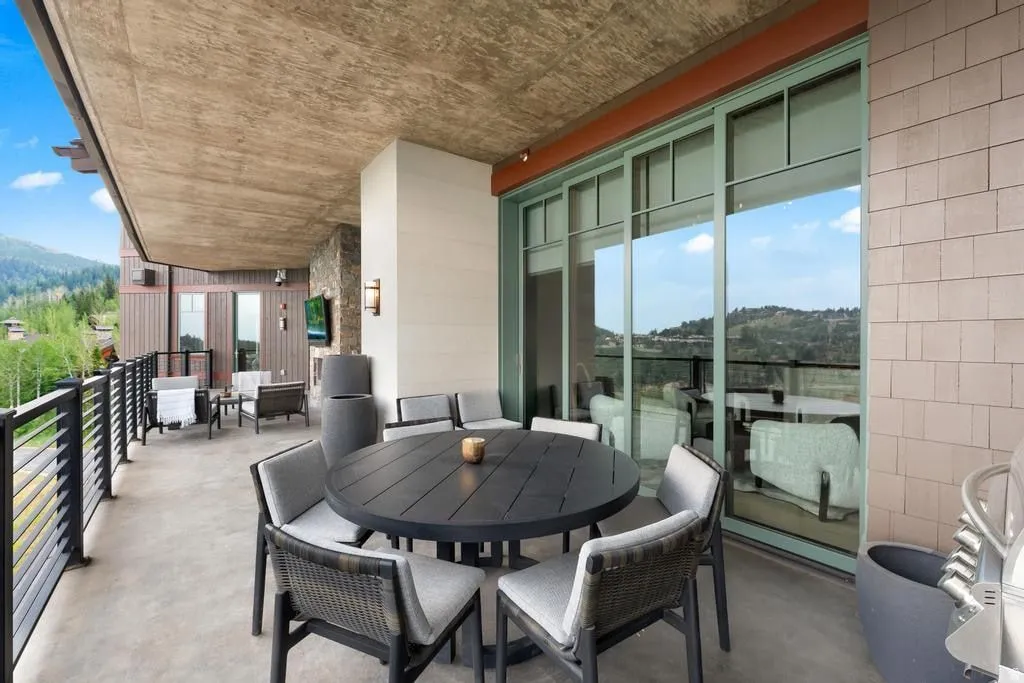 Expansive concrete patio featuring a mountain backdrop, black metal railings, and large sliding glass doors