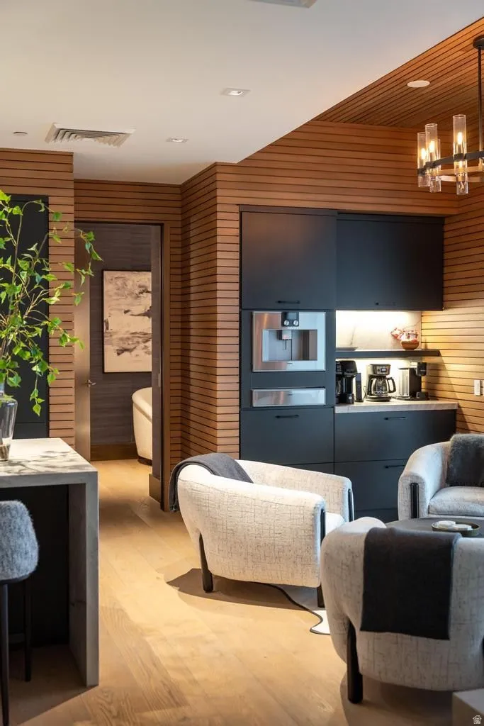 Integrated wet bar with black cabinetry, built-in coffee maker, and under-cabinet lighting