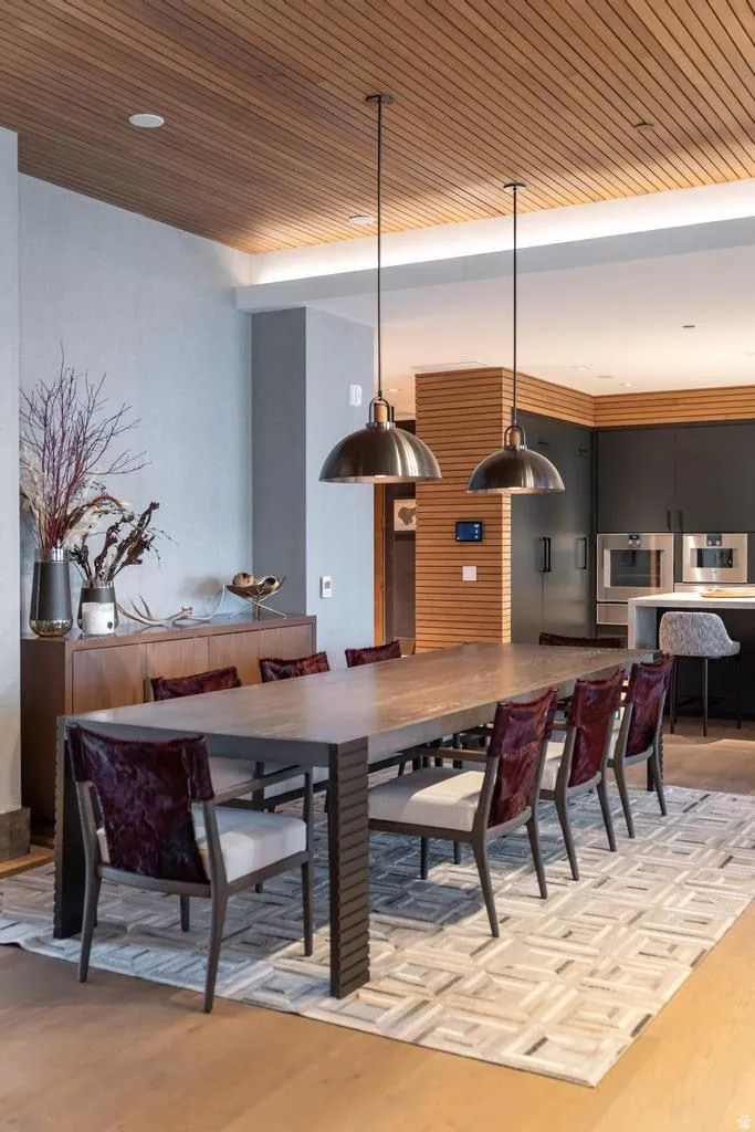 Spacious dining area featuring a wood-finish plank ceiling, two contemporary pendant light fixtures, and wide plank wood-finish flooring