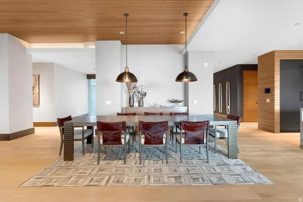 Dining area featuring a wood-panel ceiling, light wood-finish flooring, and two pendant light fixtures