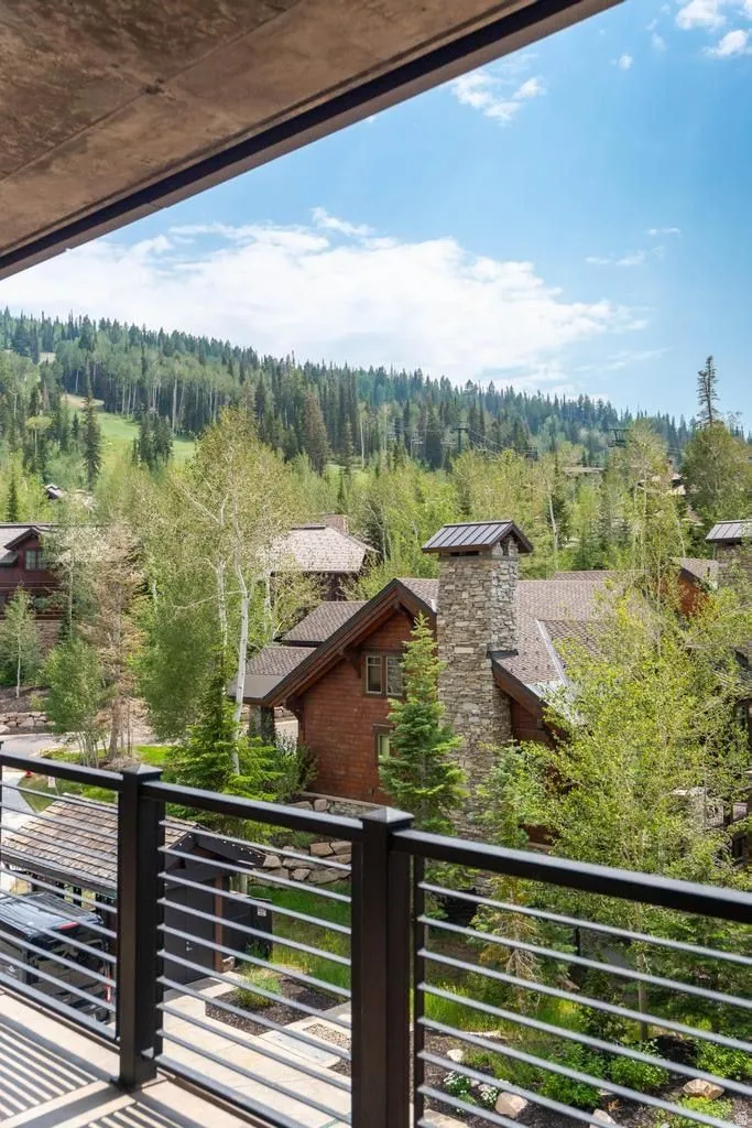 Contemporary exterior balcony with metal railing, showcasing surrounding mountainous terrain and distant architectural elements
