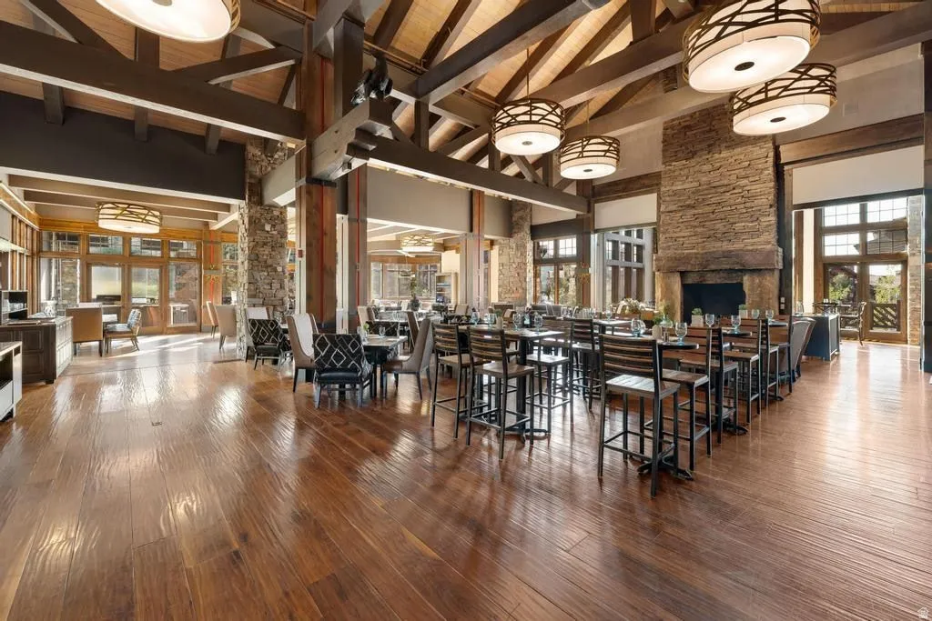 Spacious interior featuring wood-finish flooring, a stone-clad fireplace, and exposed beam ceilings