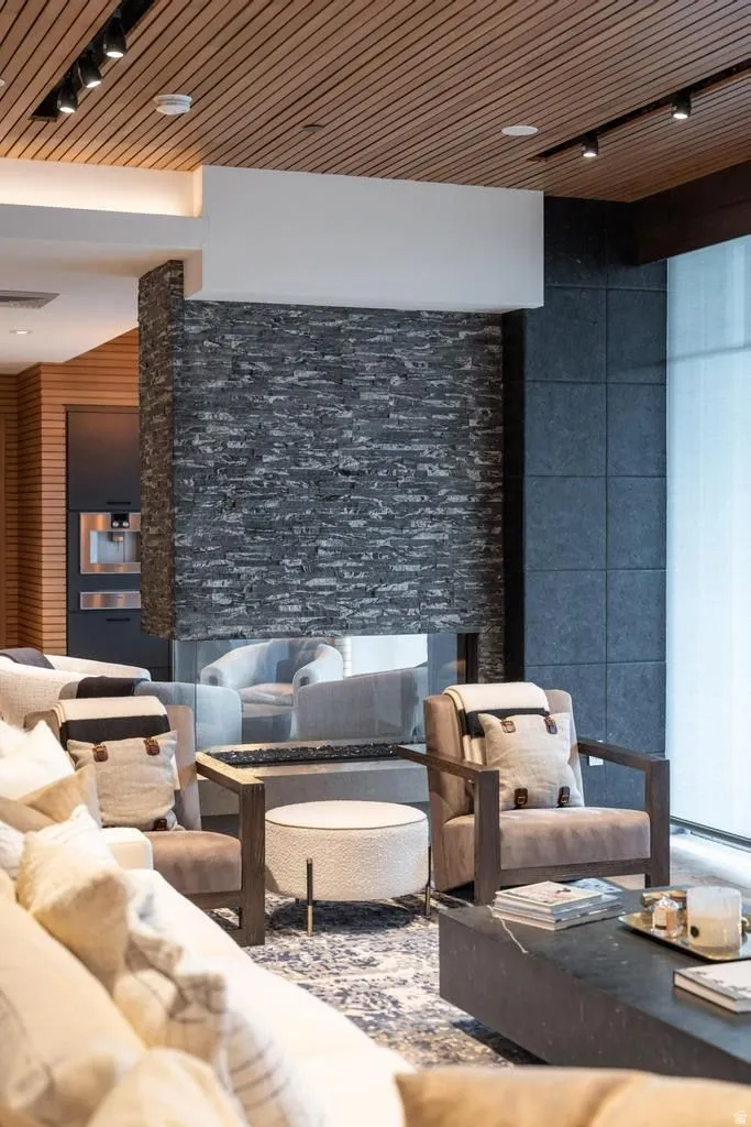 Modern living space featuring a floor-to-ceiling stone-faced fireplace with a glass barrier