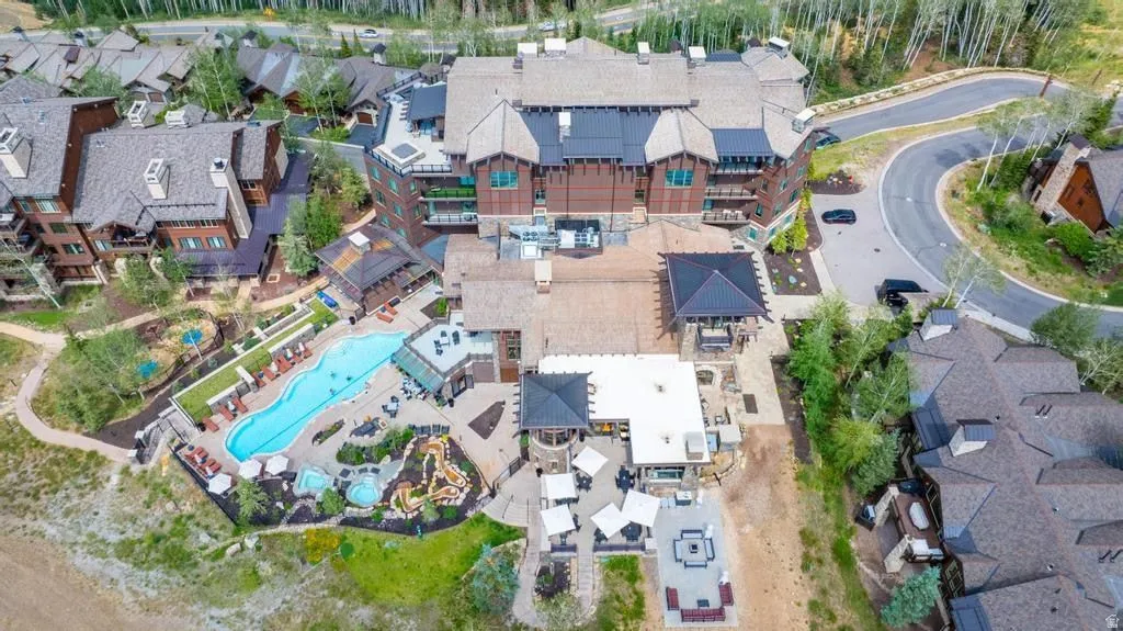 Complex featuring a large outdoor pool, multiple hot tubs, and terraced patio areas with fire pits