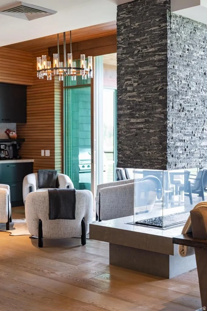 Open-concept living area featuring a stone accent wall, a contemporary chandelier, and wood-finish flooring
